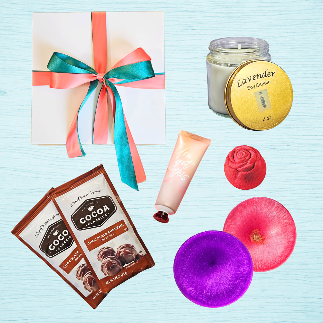Gift box with ribbon, candle, lotion, cocoa packs, resin coasters, and bath bomb on light blue background