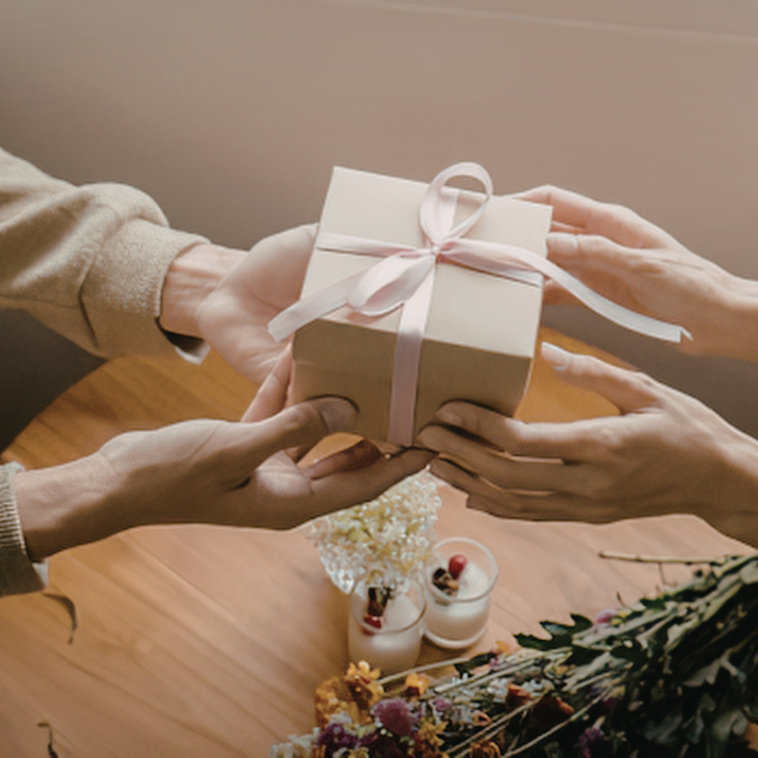 hands showing one person giving a small gift to another person