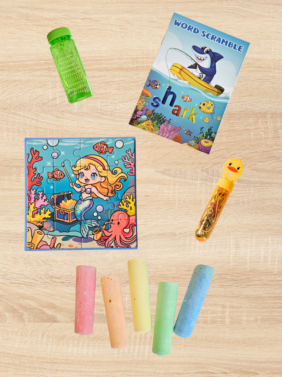 flat‑lay of kids’ bubbles, mini activity book, puzzle, bracelet kit, and sidewalk chalk on a light wood table