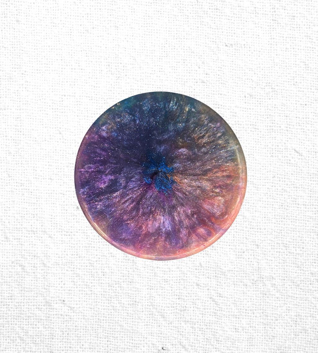 Handmade resin coaster with blues, purples, and gold crystal-burst patterns.