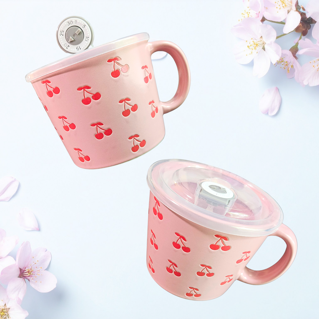 A ceramic soup mug with red cherry designs and a silicone‑sealed plastic lid featuring an adjustable dial and venting hole, available in pink or white.