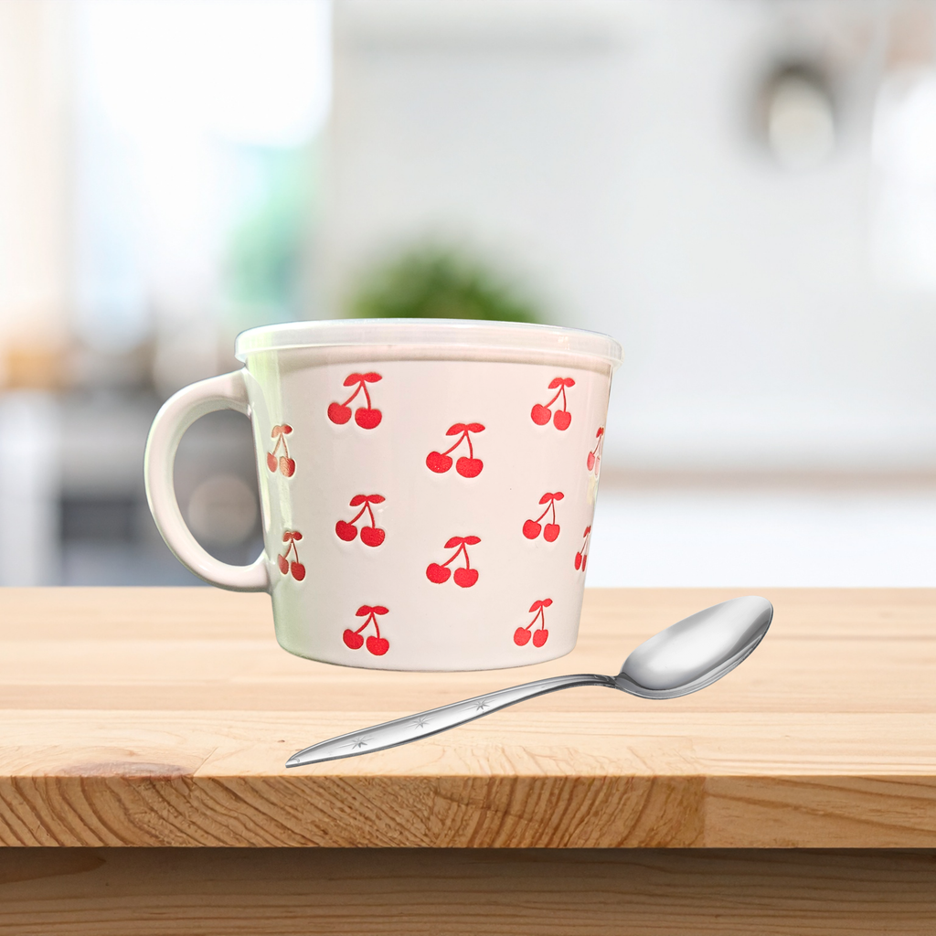 A ceramic soup mug with red cherry designs and a silicone‑sealed plastic lid featuring an adjustable dial and venting hole, available in pink or white.