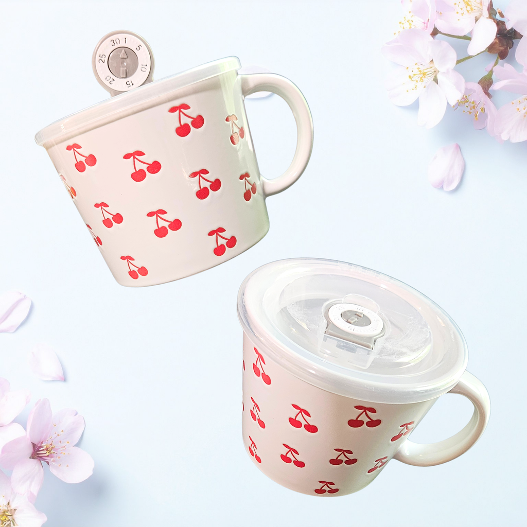 A ceramic soup mug with red cherry designs and a silicone‑sealed plastic lid featuring an adjustable dial and venting hole, available in pink or white.