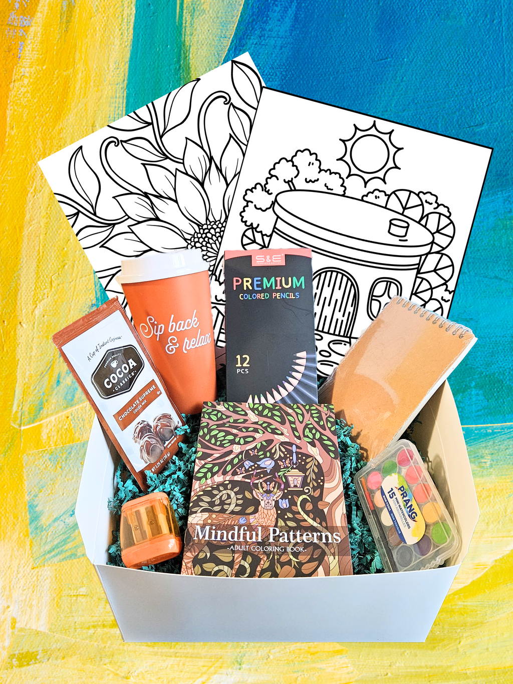 Creative Spark gift box with adult coloring book, colored pencils, sharpener, watercolors, sketch book, coloring sheets, cocoa, and Sip Back and Relax go cup