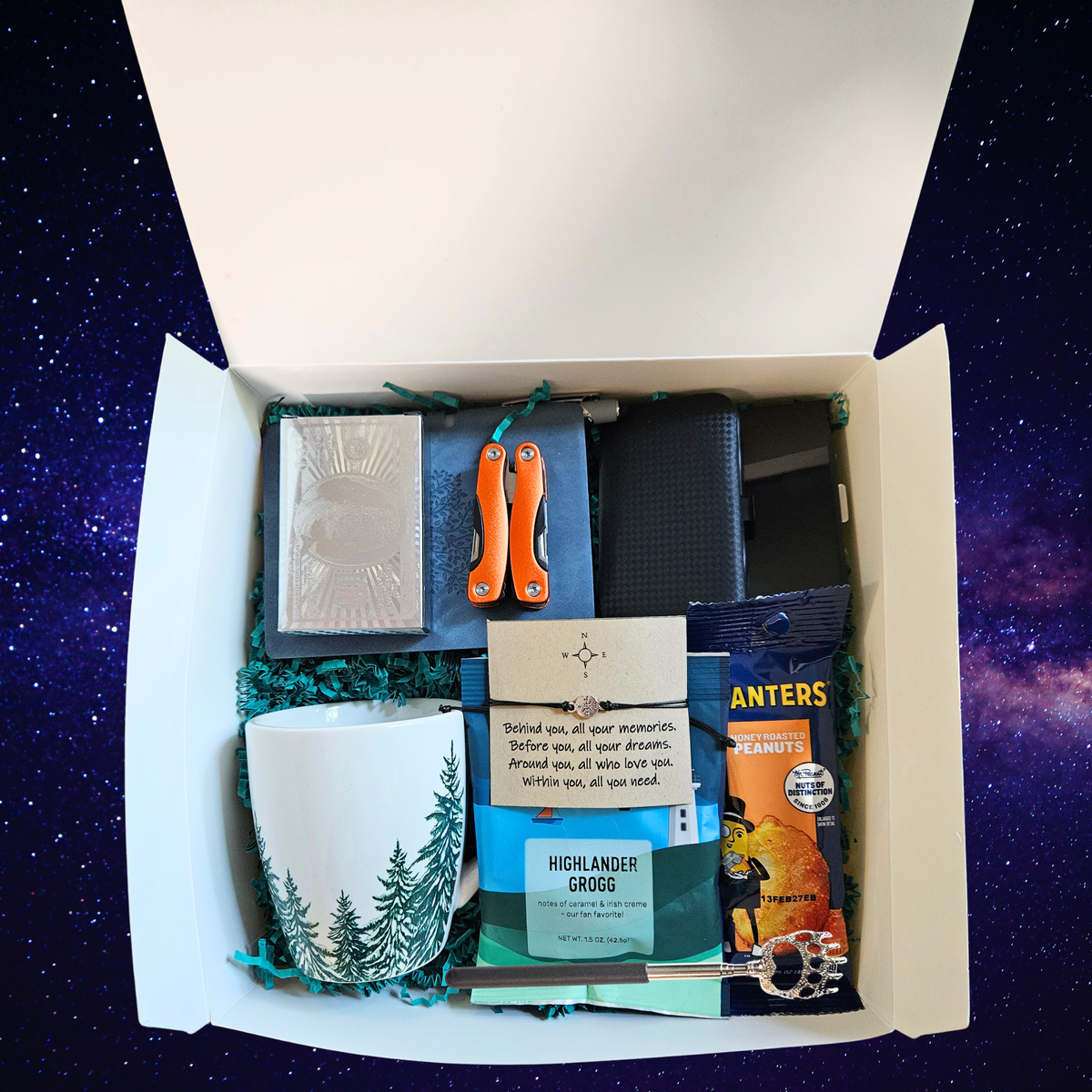 A curated gift box filled and neatly packed with various items including a white mug with a pine tree design, door county highlander grogg coffee, Planters peanuts, a multi tool, credit card carry case, boho bracelet, deck of cards, back scratcher, mini journal and manicure set, set against a starry night sky background.