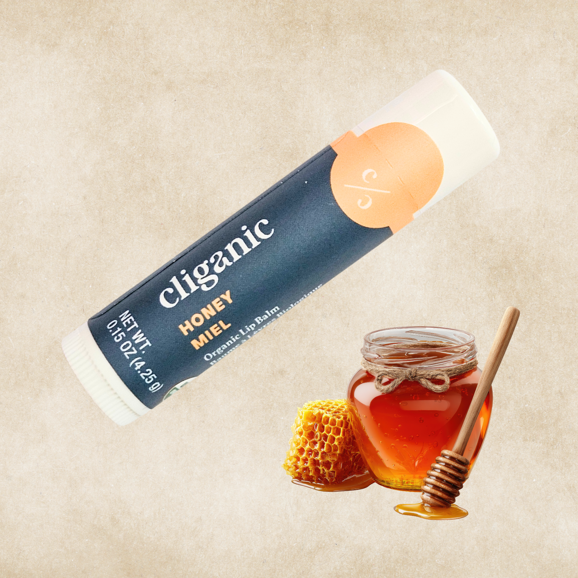 Cliganic Honey organic lip balm tube on a beige background with a honey jar, honey dipper, and honeycomb beside it.