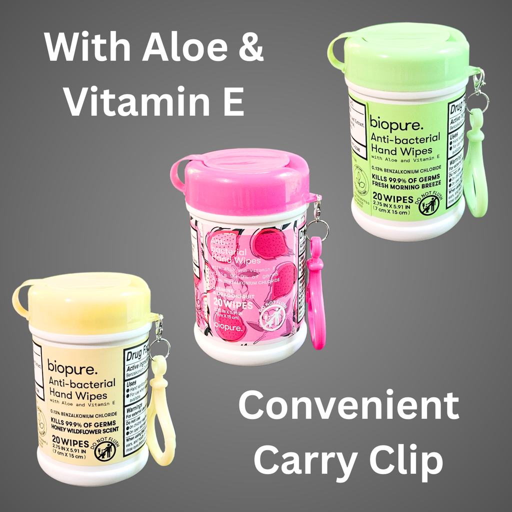 Three small BioPure anti-bacterial hand wipe containers with colored lids and matching carry clips—green, pink, and yellow—arranged together on a gray background with text highlighting aloe, vitamin E, and the convenient carry clip.