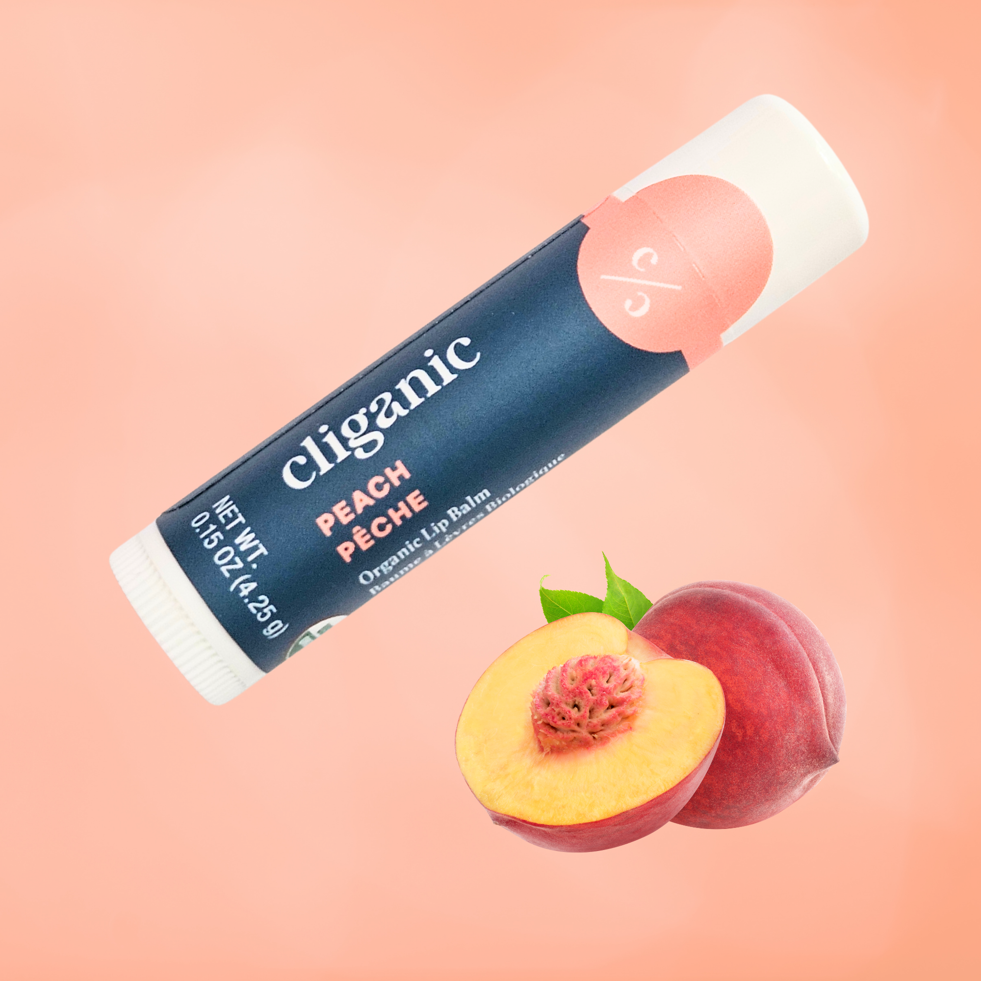 Cliganic Peach organic lip balm tube on a peach‑colored background with a whole peach and a sliced peach beneath it.