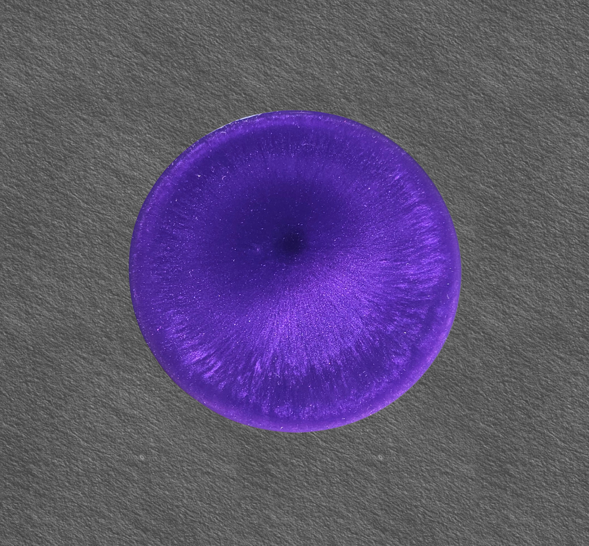 Handmade purple resin coaster with radiant crystal‑burst patterns on a dark background.