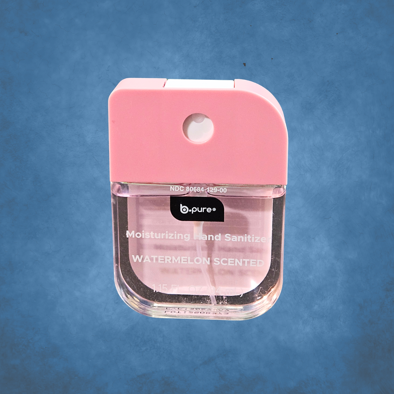 Pocket size watermelon scent pink spray hand sanitizer on a blue background.