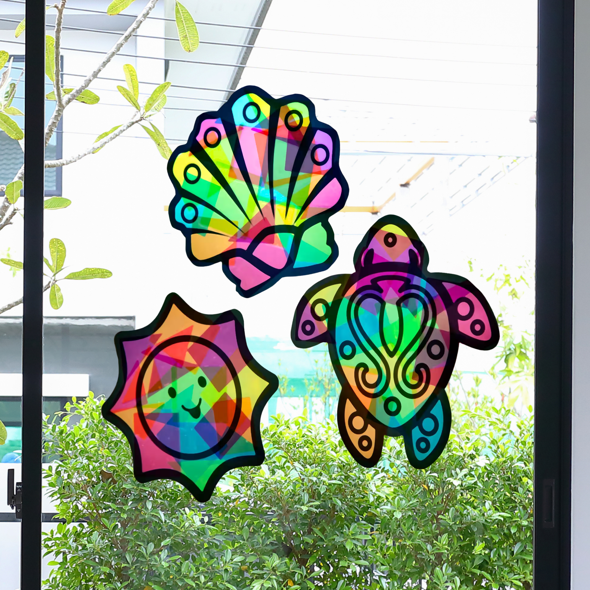Colorful turtle, sun, and shell window decorations on a glass door.