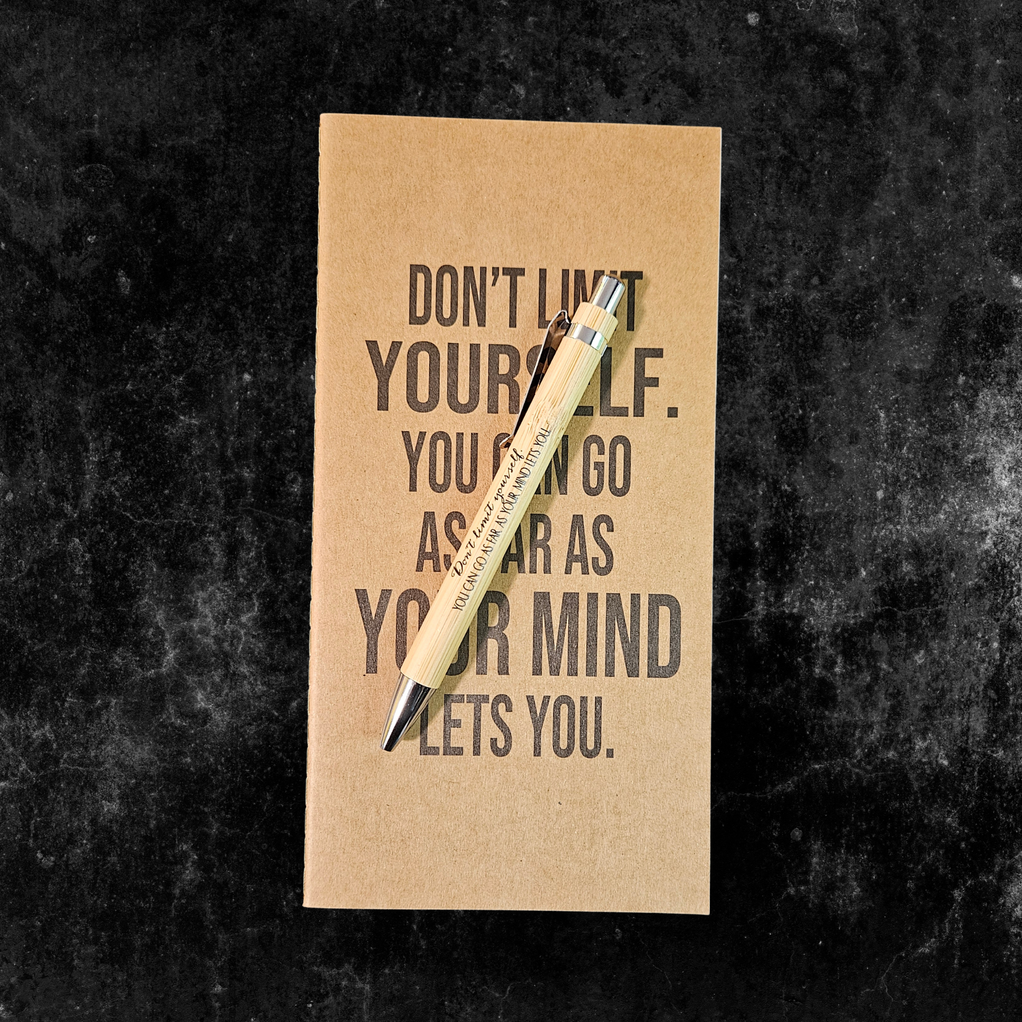 Kraft planner with motivational quote, Don't limit yourself. you can go as far as your mind lets you, and pen on a dark textured background
