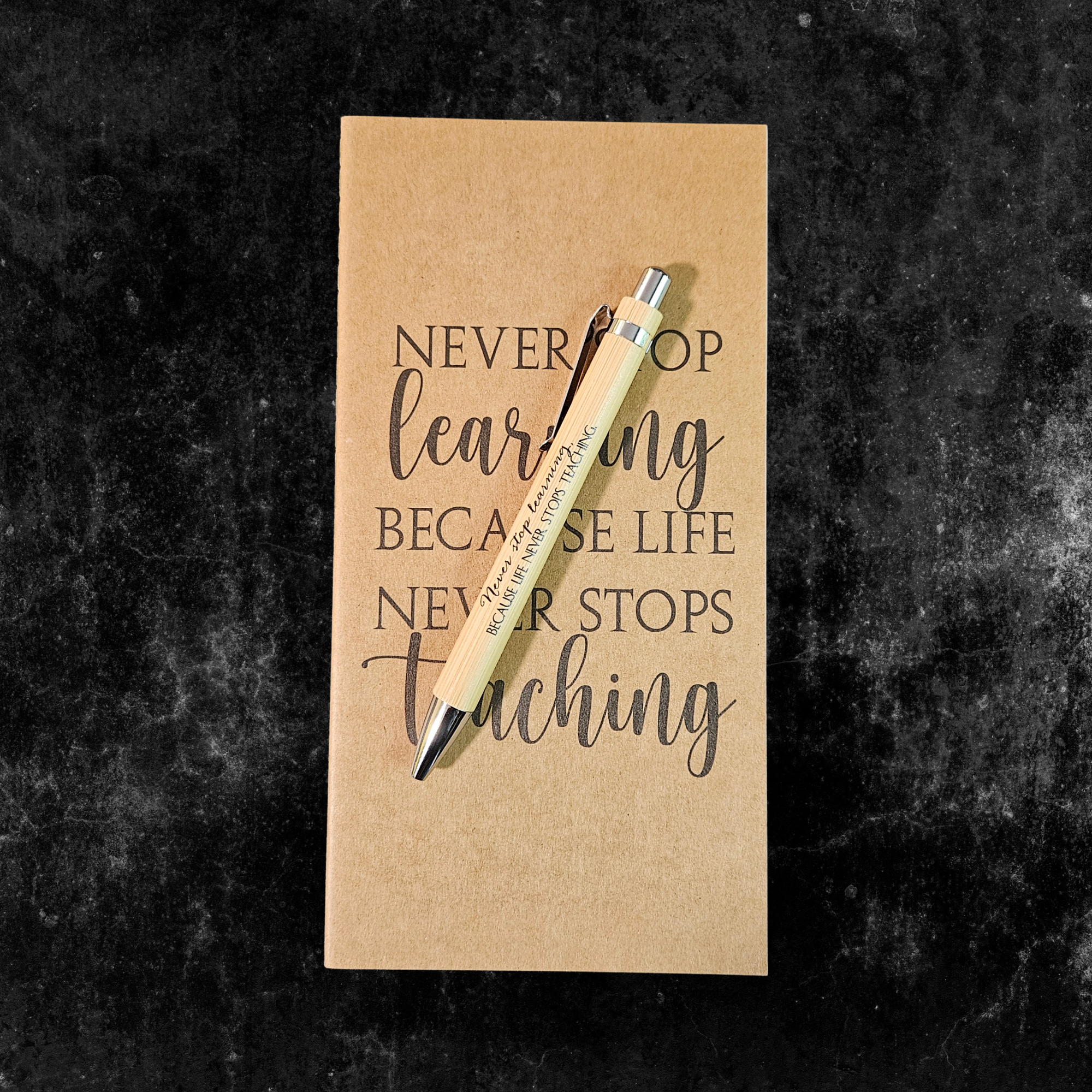Kraft planner with motivational quote, Never stop learning because life never stops teaching, and pen on a dark textured background